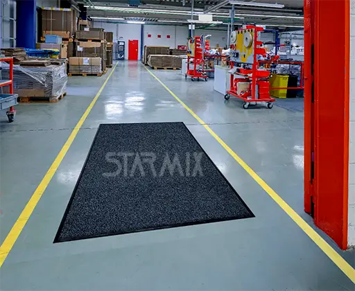 Tapete absorvente industrial STARMIX em corredor de fábrica retendo óleo água e sujeira em área de alto tráfego